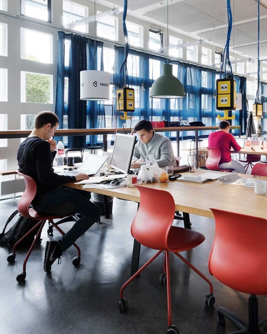Junge Gründer sitzen in einem modern eingerichteten Inkubator und arbeiten.