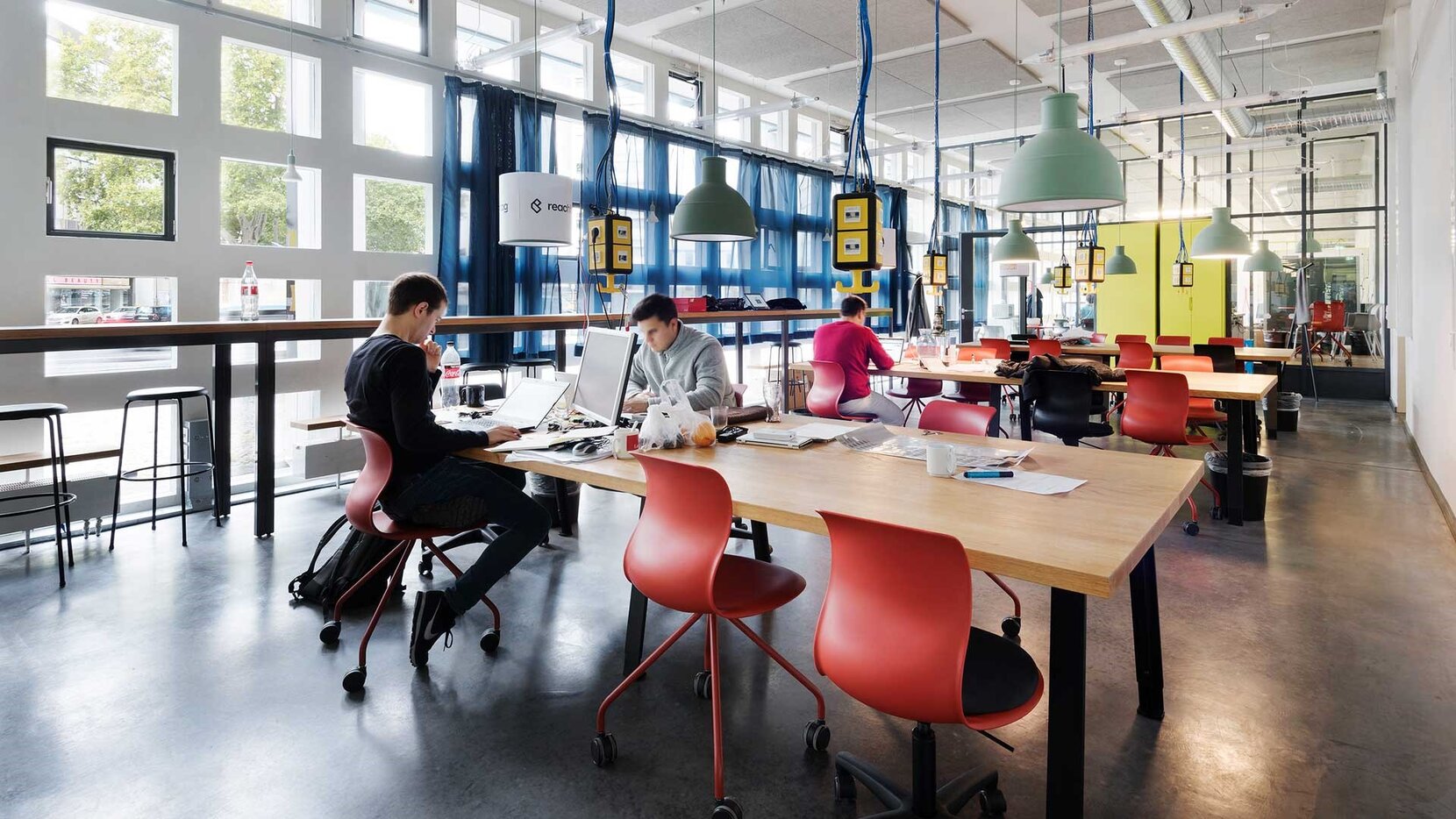 Junge Gründer sitzen in einem modern eingerichteten Inkubator und arbeiten.
