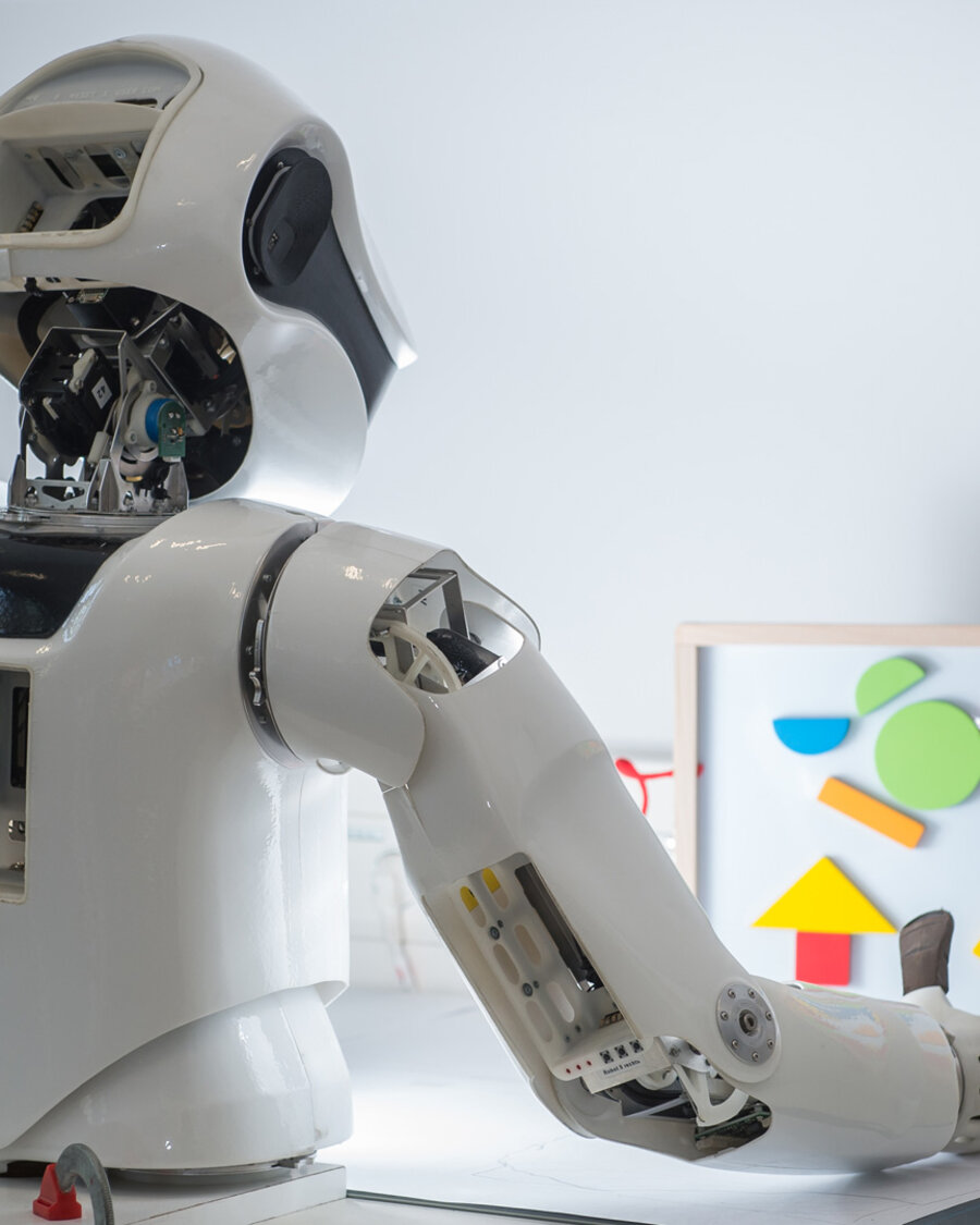 Humanoider Roboter vor einer Tafel mit geometrischen Elementen