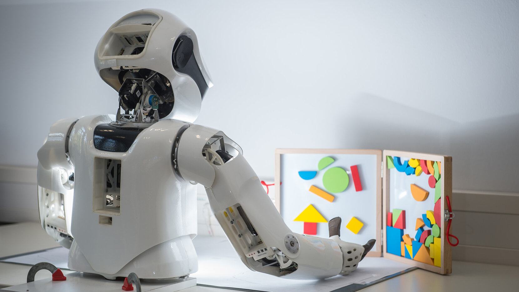 Humanoider Roboter vor einer Tafel mit geometrischen Elementen