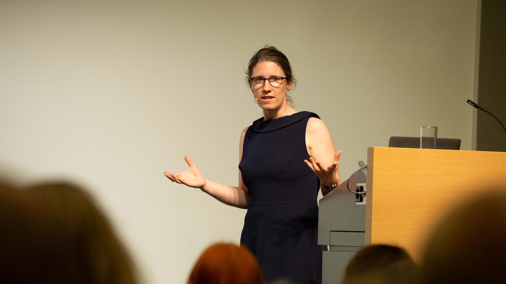 Prof. Dr. Barbara Vetter, Professorin für Theoretische Philosophie an der FU Berlin hält einen Vortrag. Sie trägt ein schwarzes Kleid und gestikuliert in Richtung Publikum, Brain City Berlin.