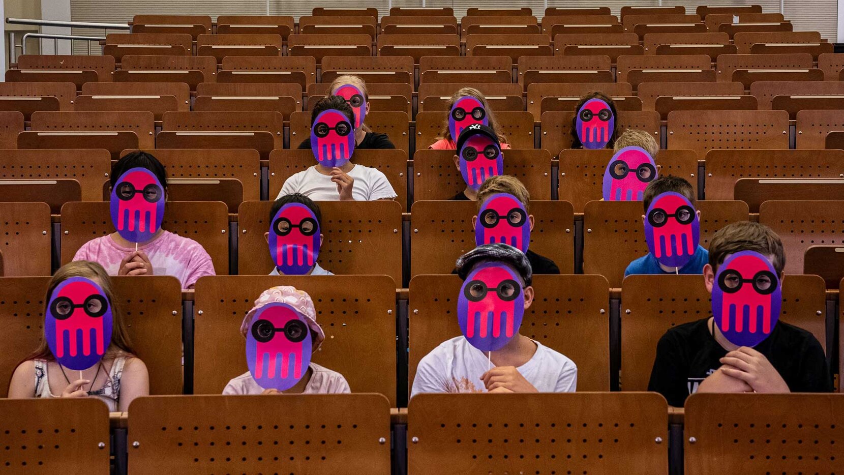 Kinder mit KUL-Masken im Hörsaal.